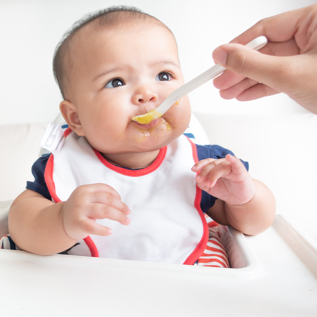 baby with white bib being fed
