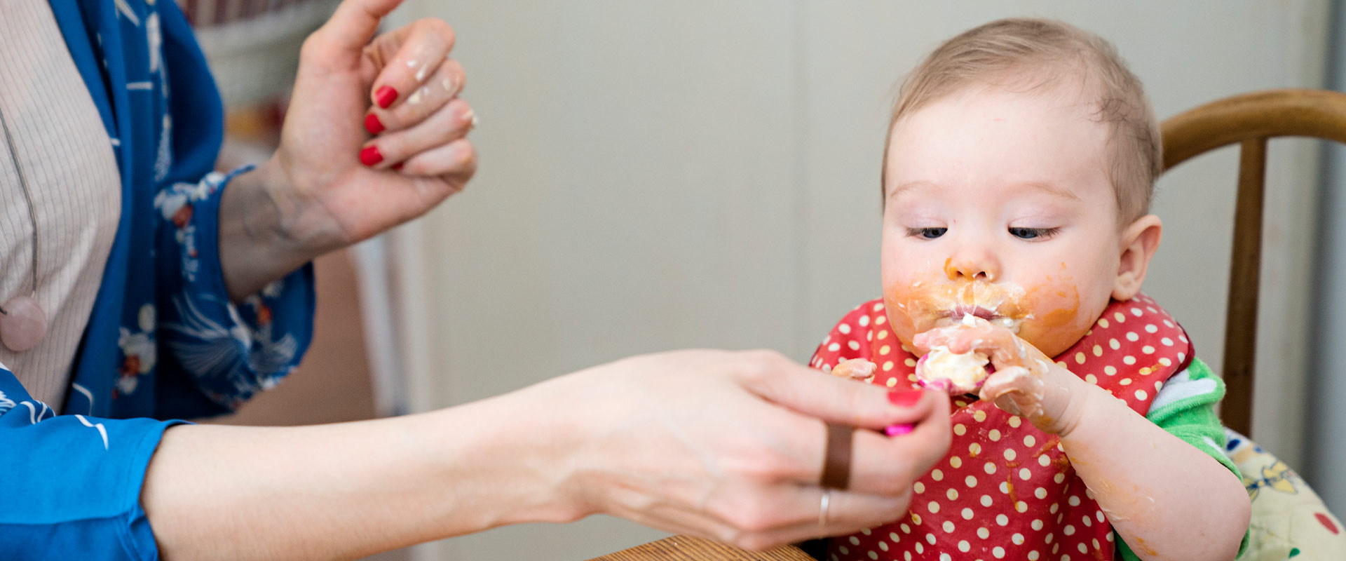 Baby with dotted bib eating at table
