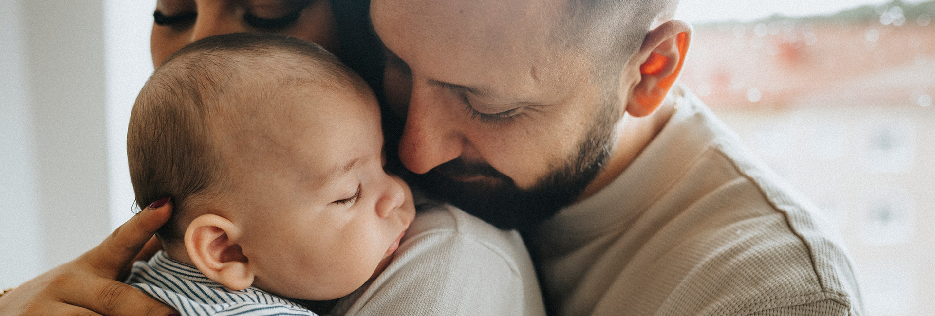 baby sleeping on mothers shoulder, father close 